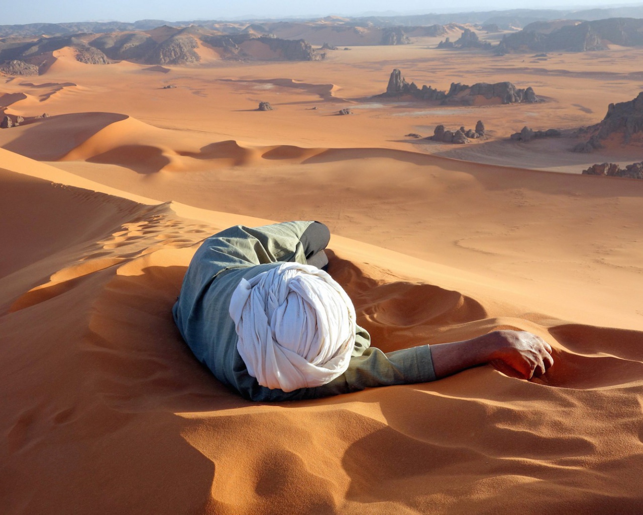 Человек лежит на песке в пустыне