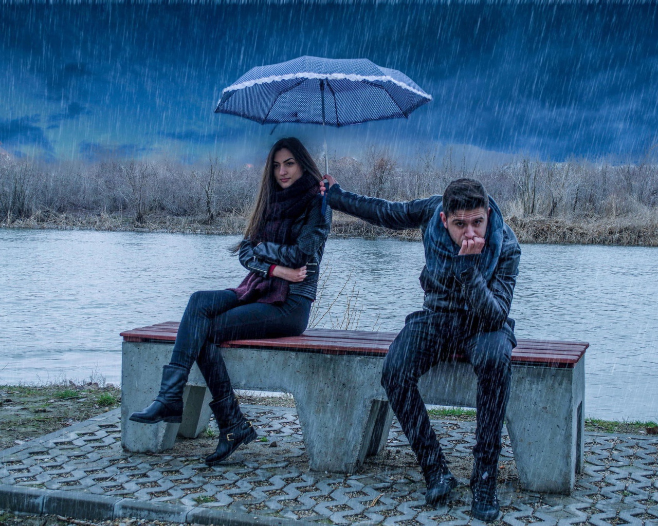 Парень держит над девушкой зонт во время дождя