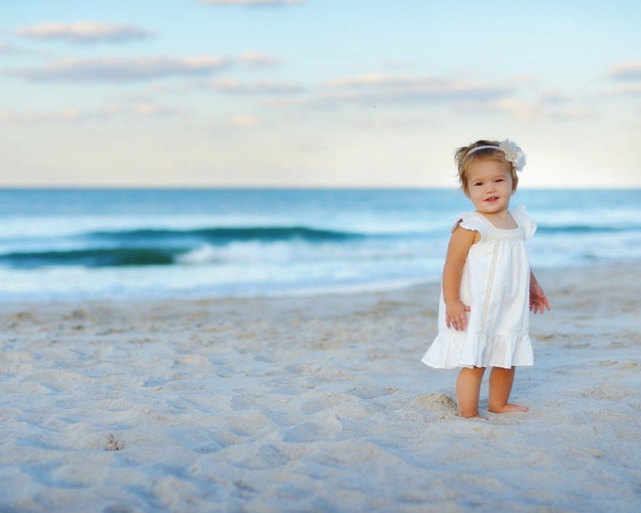 Девочка в белом платье на песке пляжа
