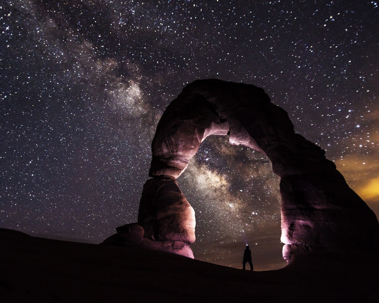 Природная каменная арка на фоне звезд