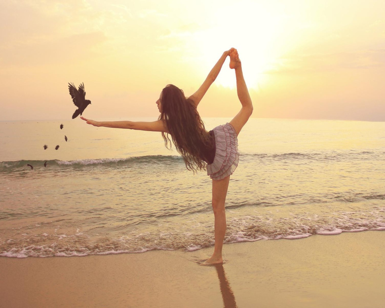 Балерина на берегу моря с птицей