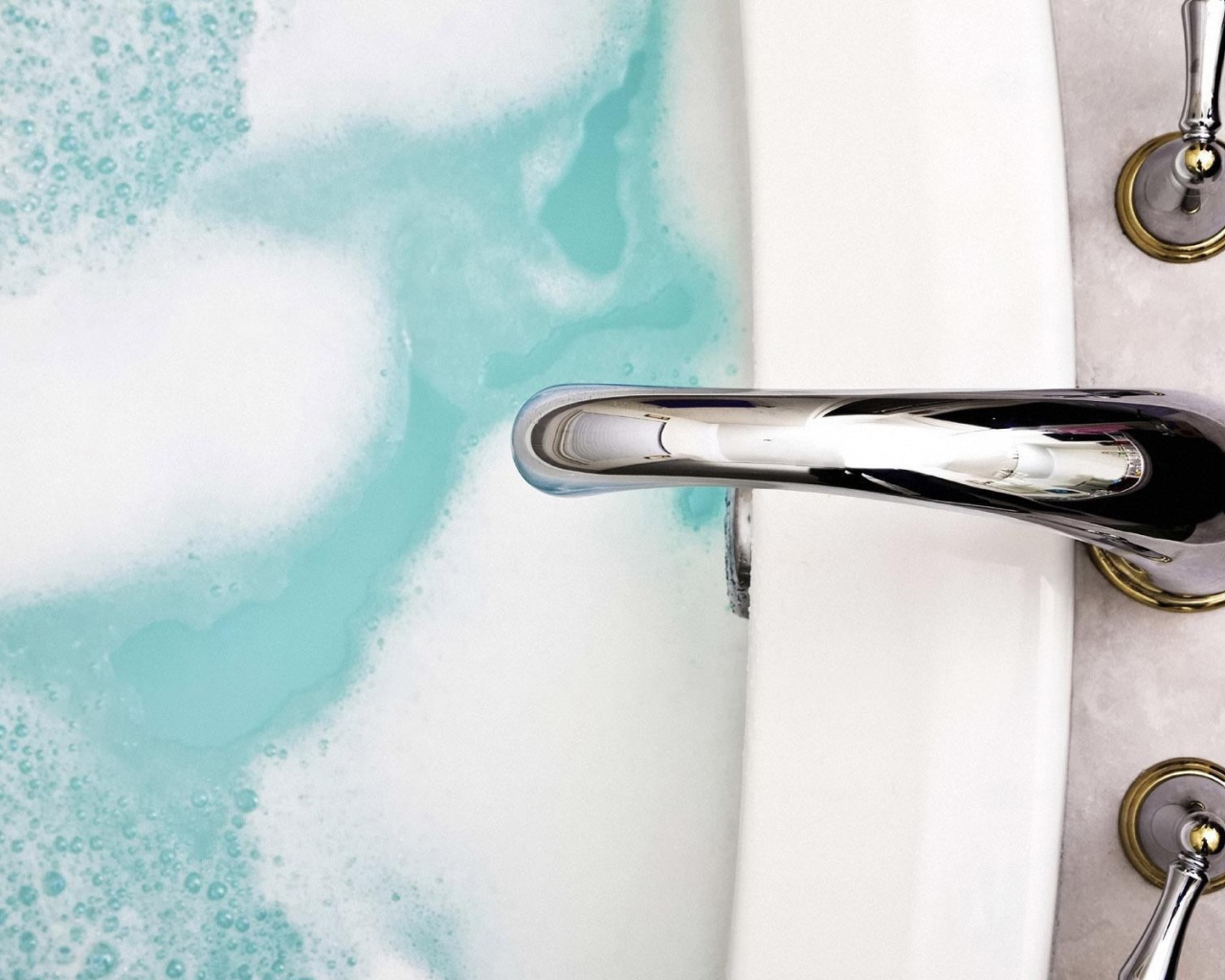 Кран над ванной с голубой водой