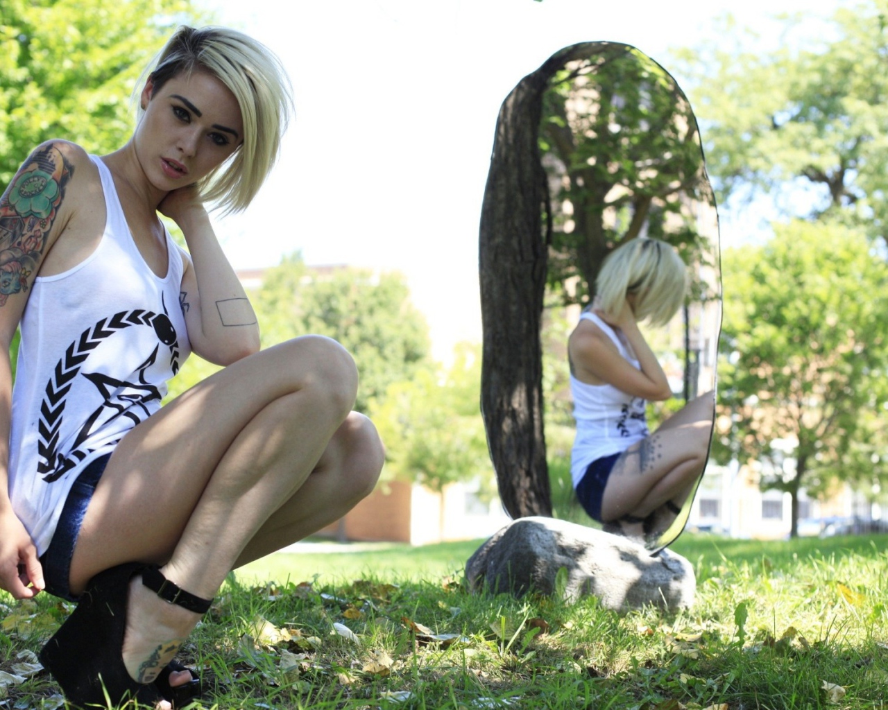 Девушка с тату на природе у зеркала