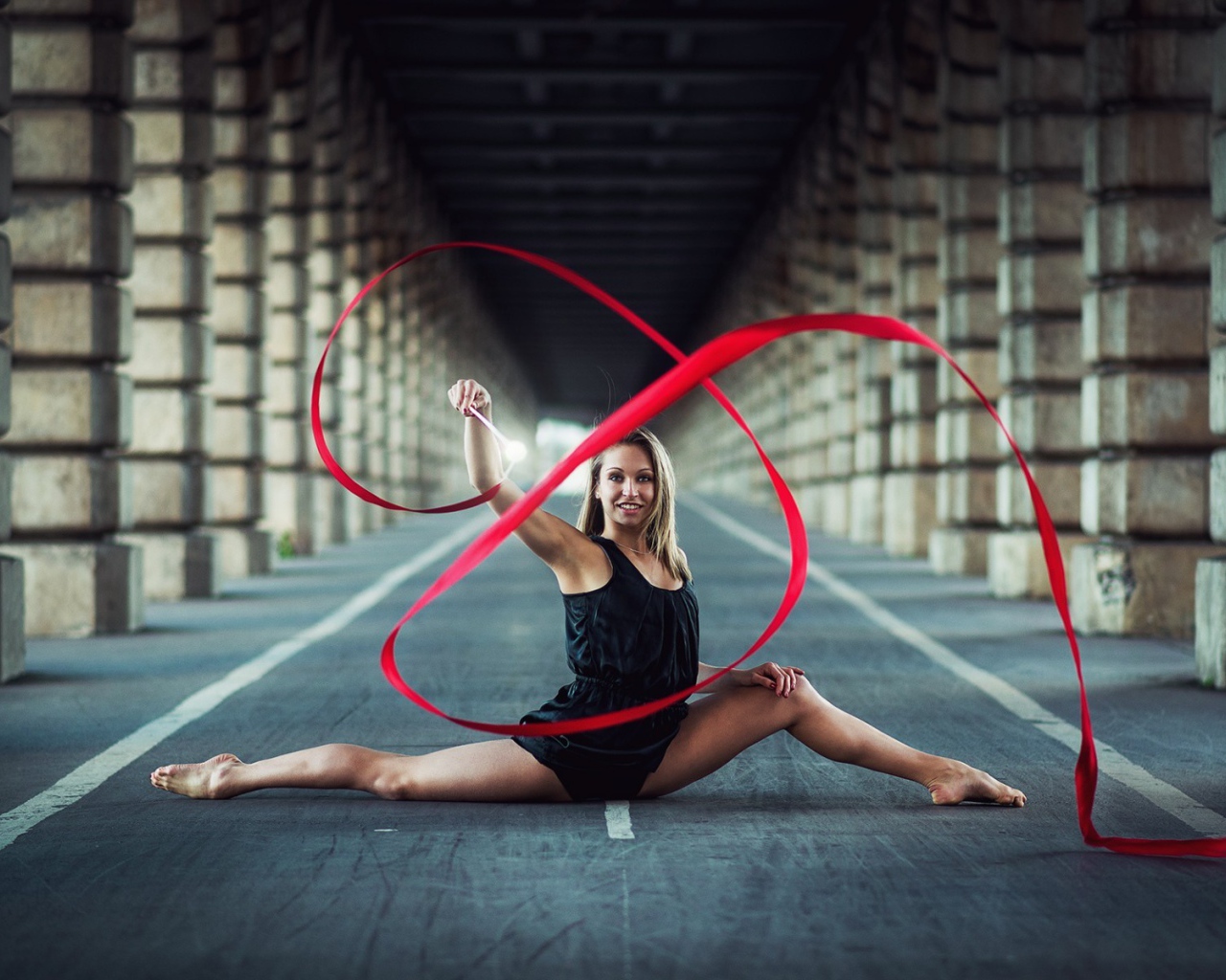 Гимнастка упражняется с красной лентой