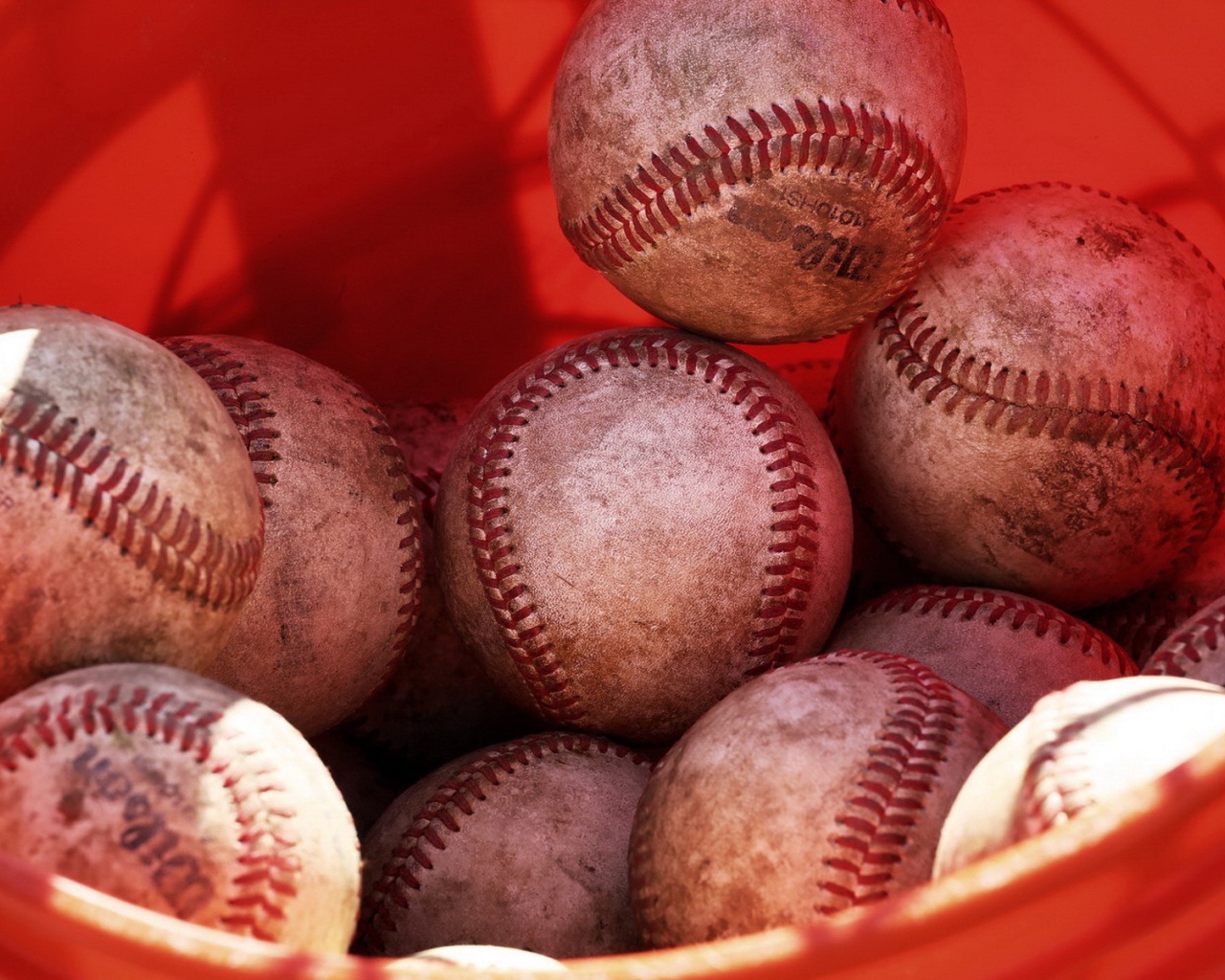 Красное ведро с мячами для бейсбола