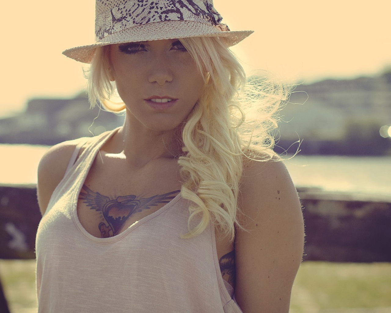 Блондинка в белой шляпе с тату на груди