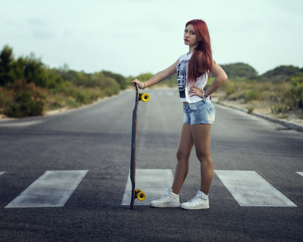 Девушка со скейтбордом стоит на переходе