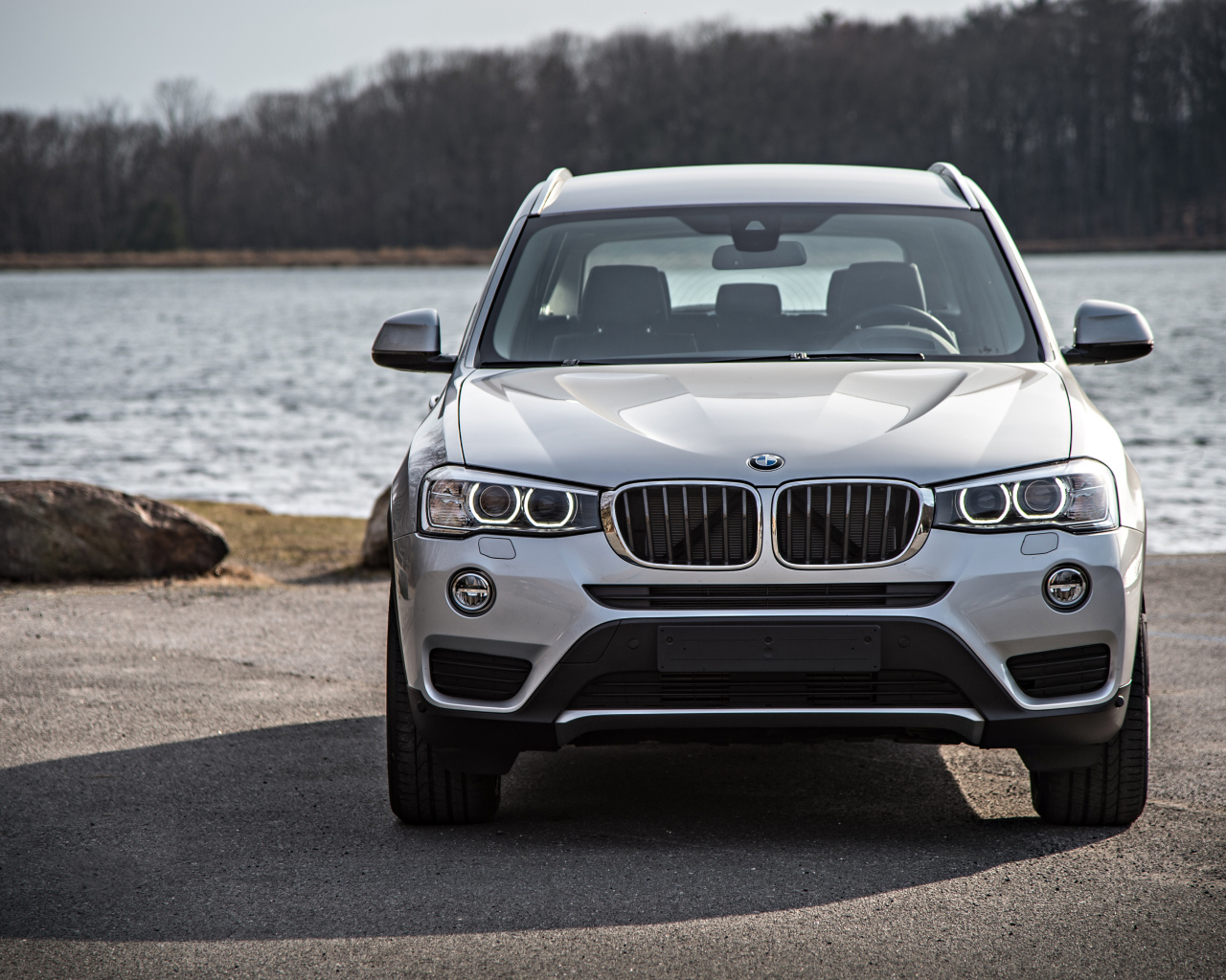 Серебристый автомобиль BMW X3 у водоема 