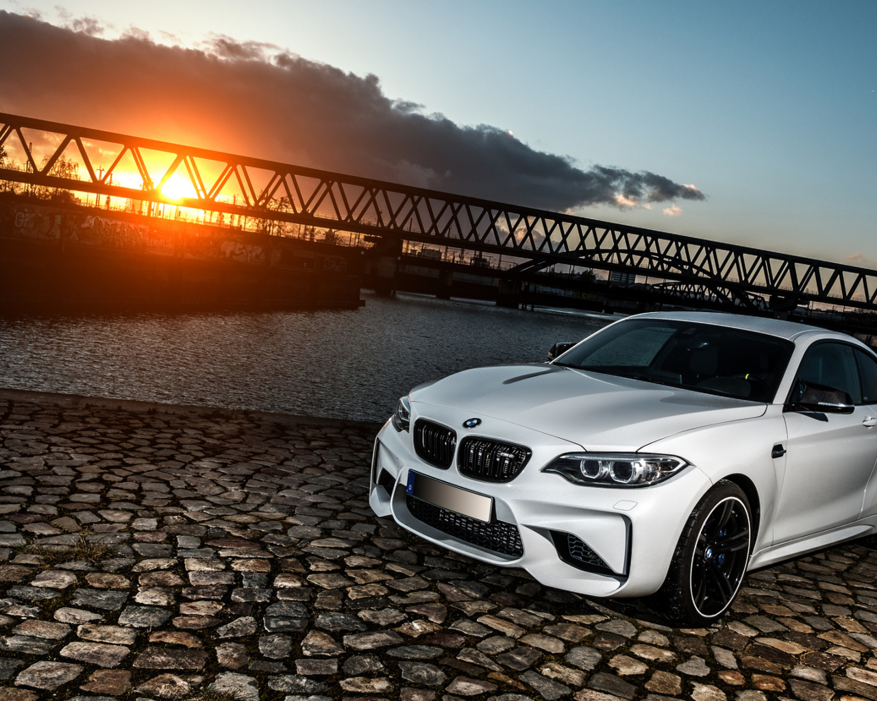 Белый автомобиль BMW M2 на фоне заката 