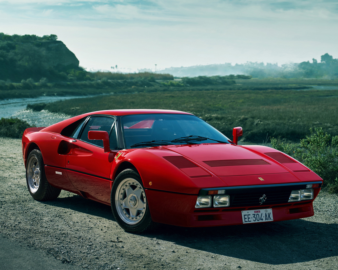 Красный быстрый автомобиль Ferrari 288 GTO у реки