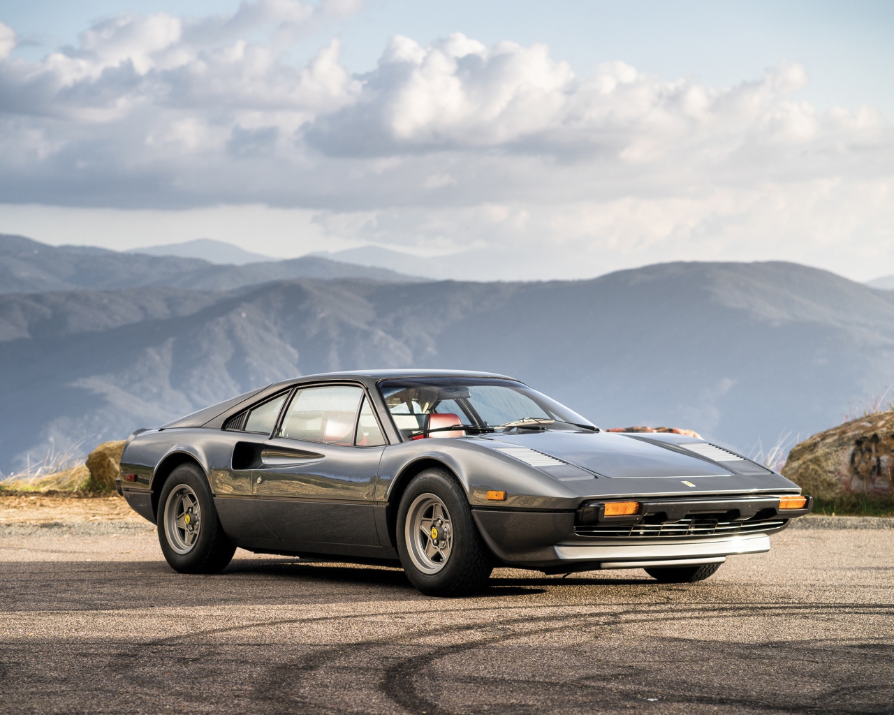 Суперкар Ferrari 308 gts серого цвета,   на фоне гор 