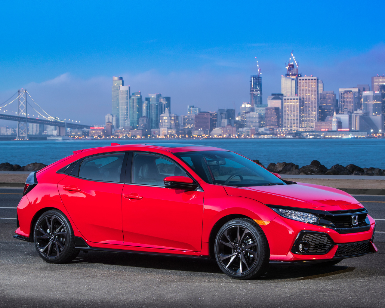 Красный автомобиль Honda Civic Touring Hatchback, 2017 на фоне города 