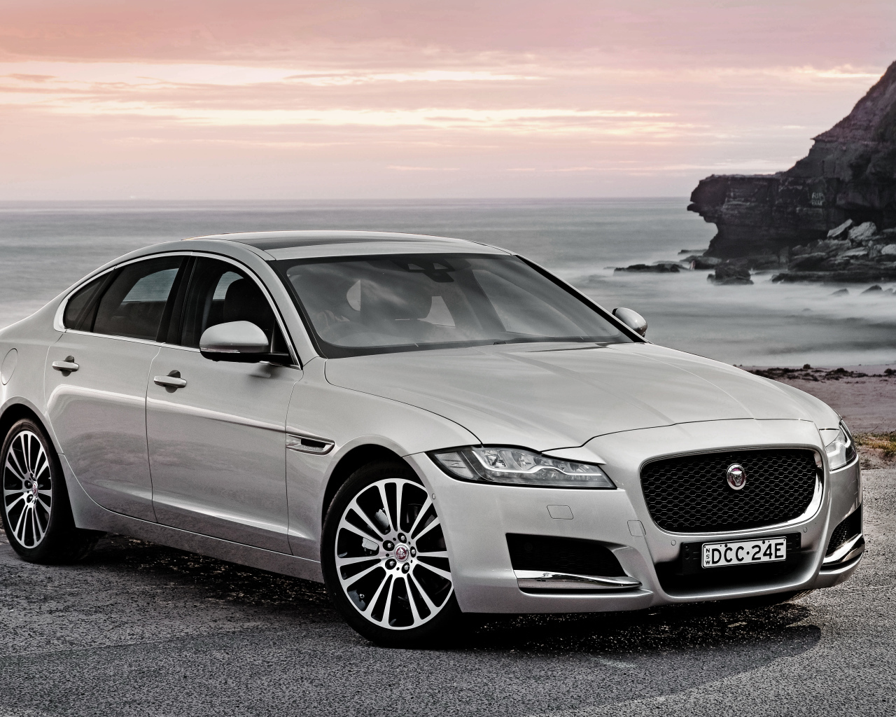 Серебристый автомобиль Jaguar XF на фоне океана