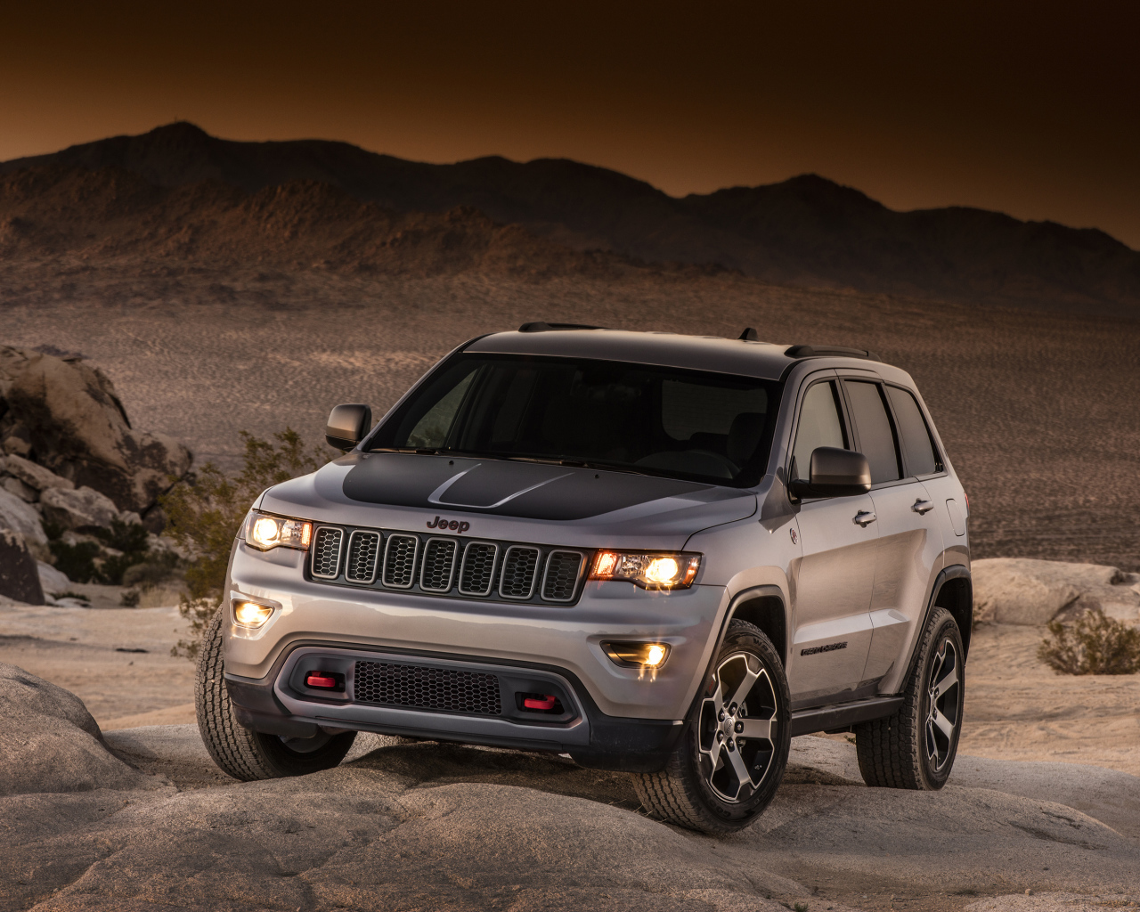 Серебристый внедорожник Jeep Grand Cherokee в пустыне 