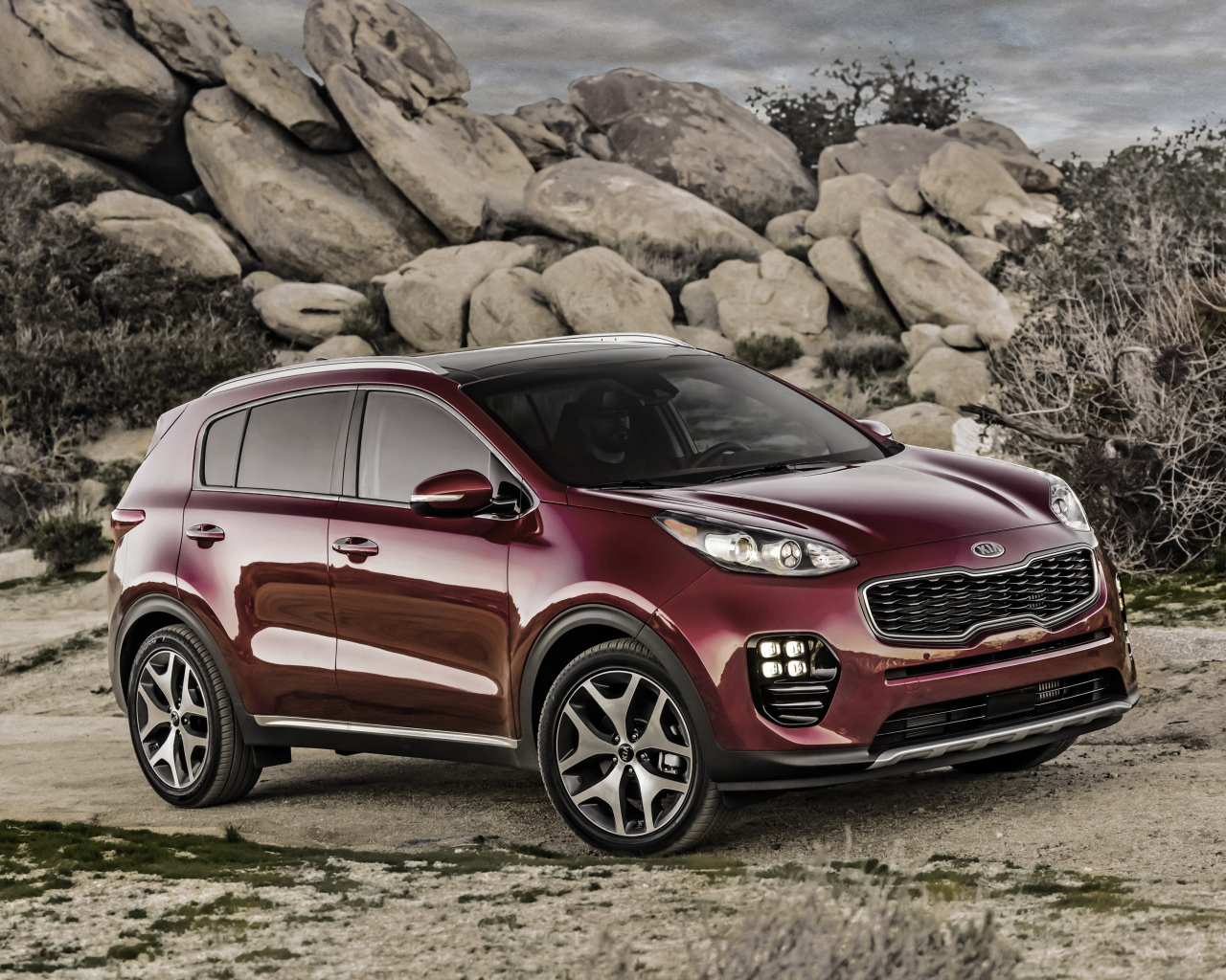 Стильный бордовый внедорожник Kia Sportage на фоне больших камней