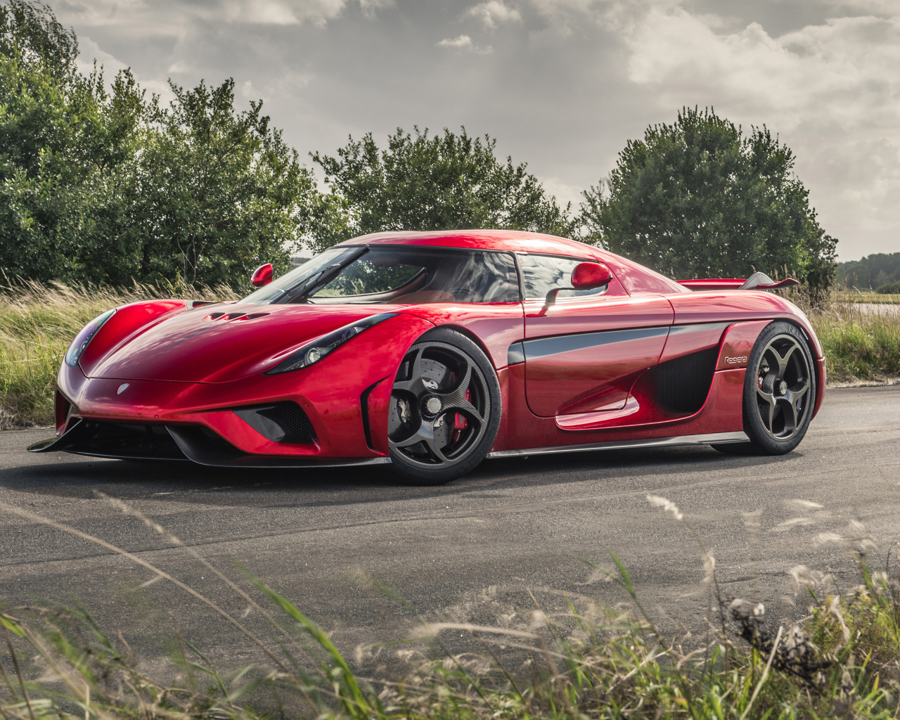 Красный спортивный автомобиль Koenigsegg Regera на дороге