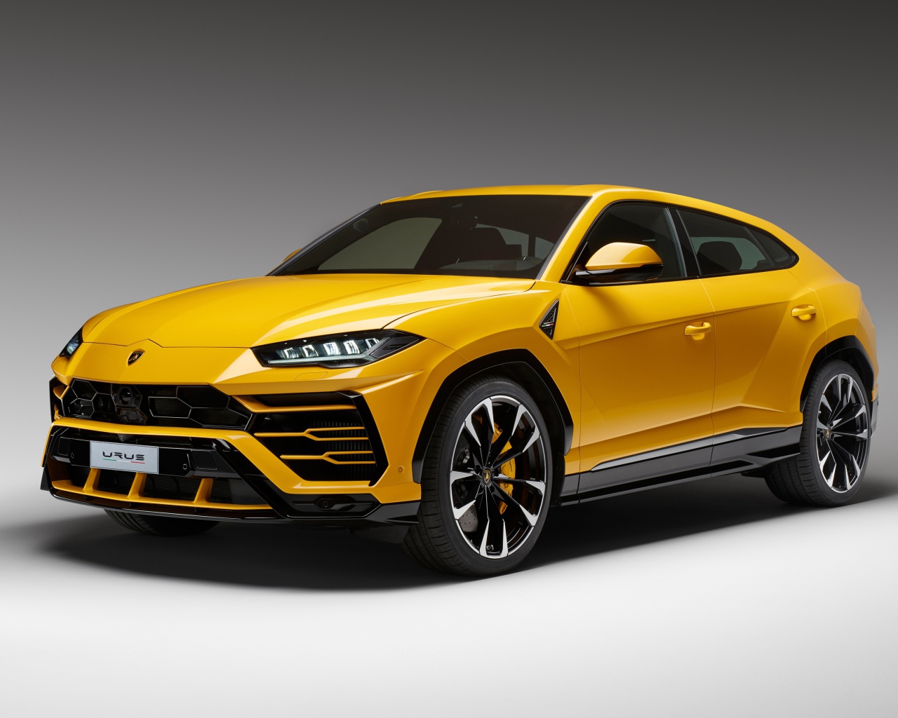 Желтый спортивный автомобиль Lamborghini Urus, 2018 на сером фоне