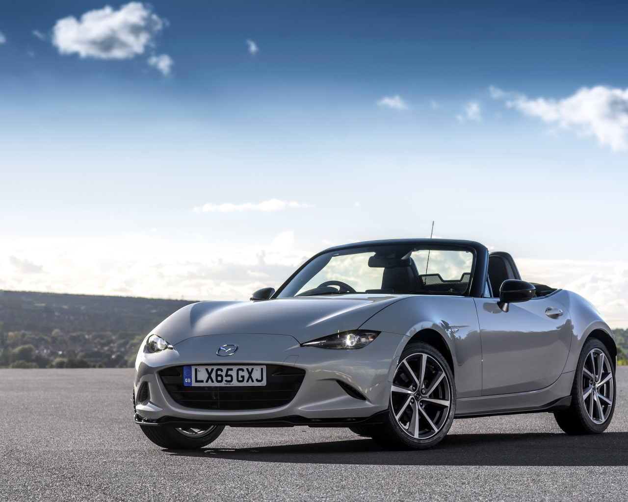 Mazda MX-5 silver cabriolet on the background of a beautiful sky