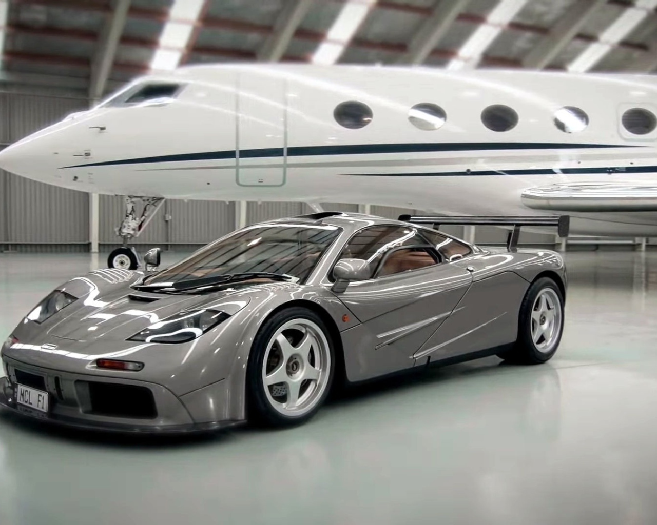 Спортивный автомобиль McLaren F1 на фоне самолета