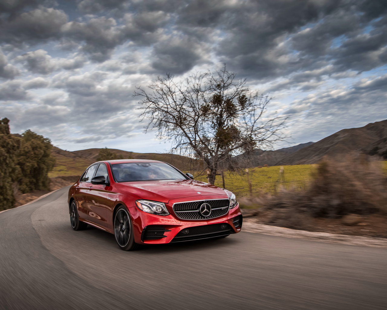 Стильный красный автомобиль Mercedes-Benz E-Class на фоне неба 