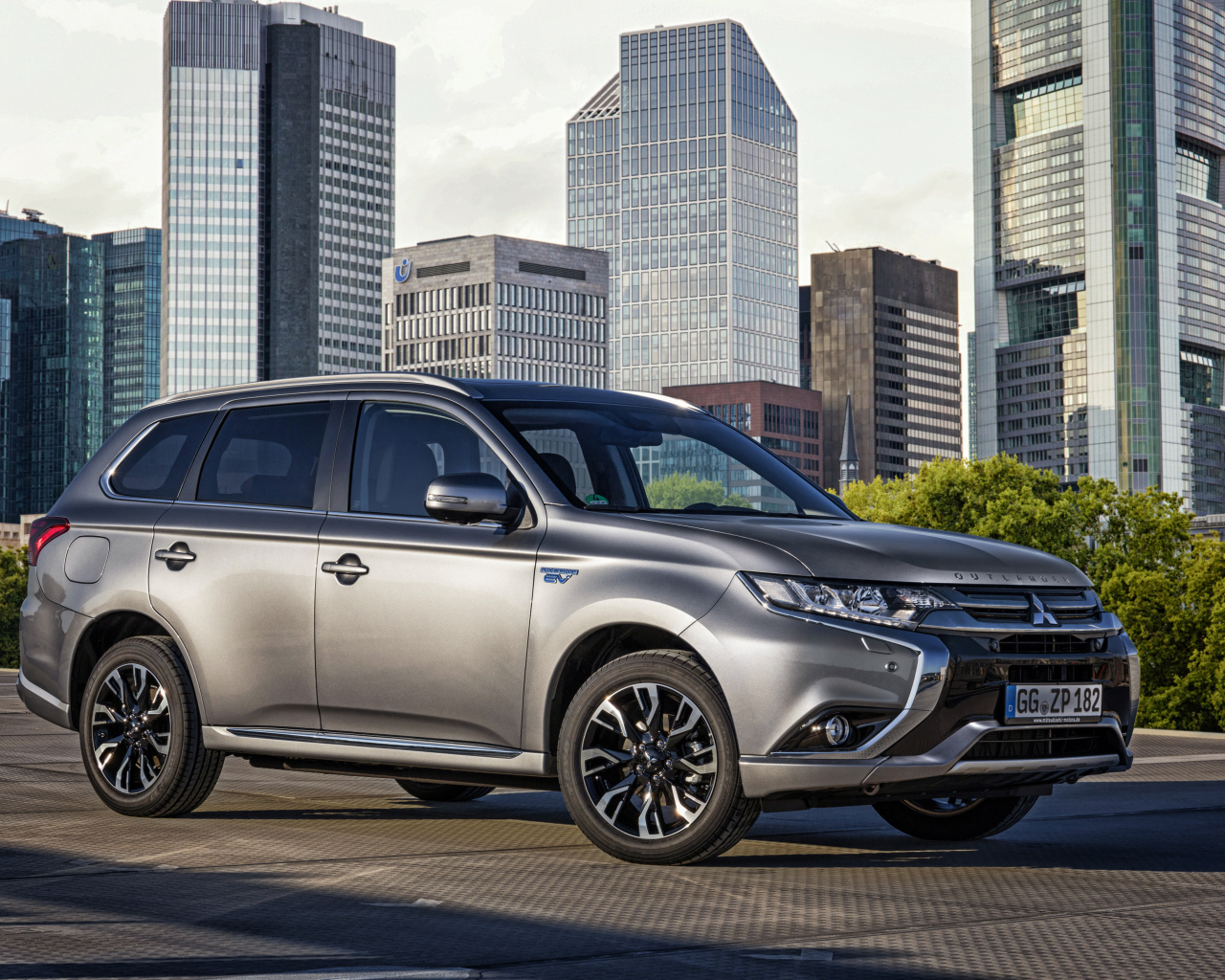 Серебристый автомобиль Mitsubishi Outlander на фоне небоскребов 