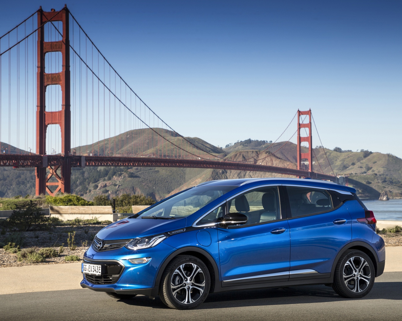 Синий автомобиль Opel Ampera-e, 2017  года на фоне моста 