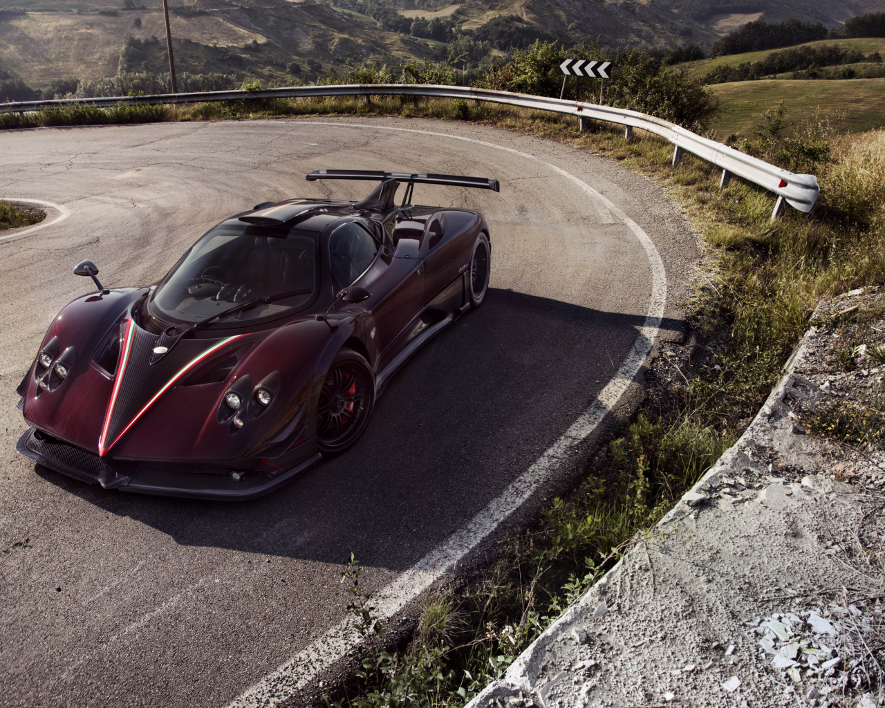 Быстрый бордовый автомобиль Pagani Zonda на крутом повороте