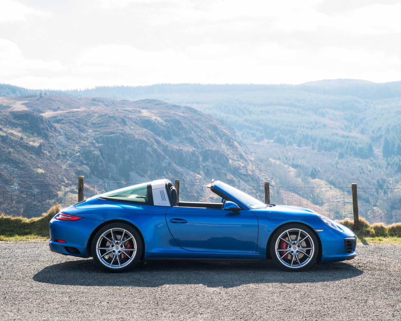Голубой автомобиль кабриолет Porsche 911 Targa 4S на фоне гор