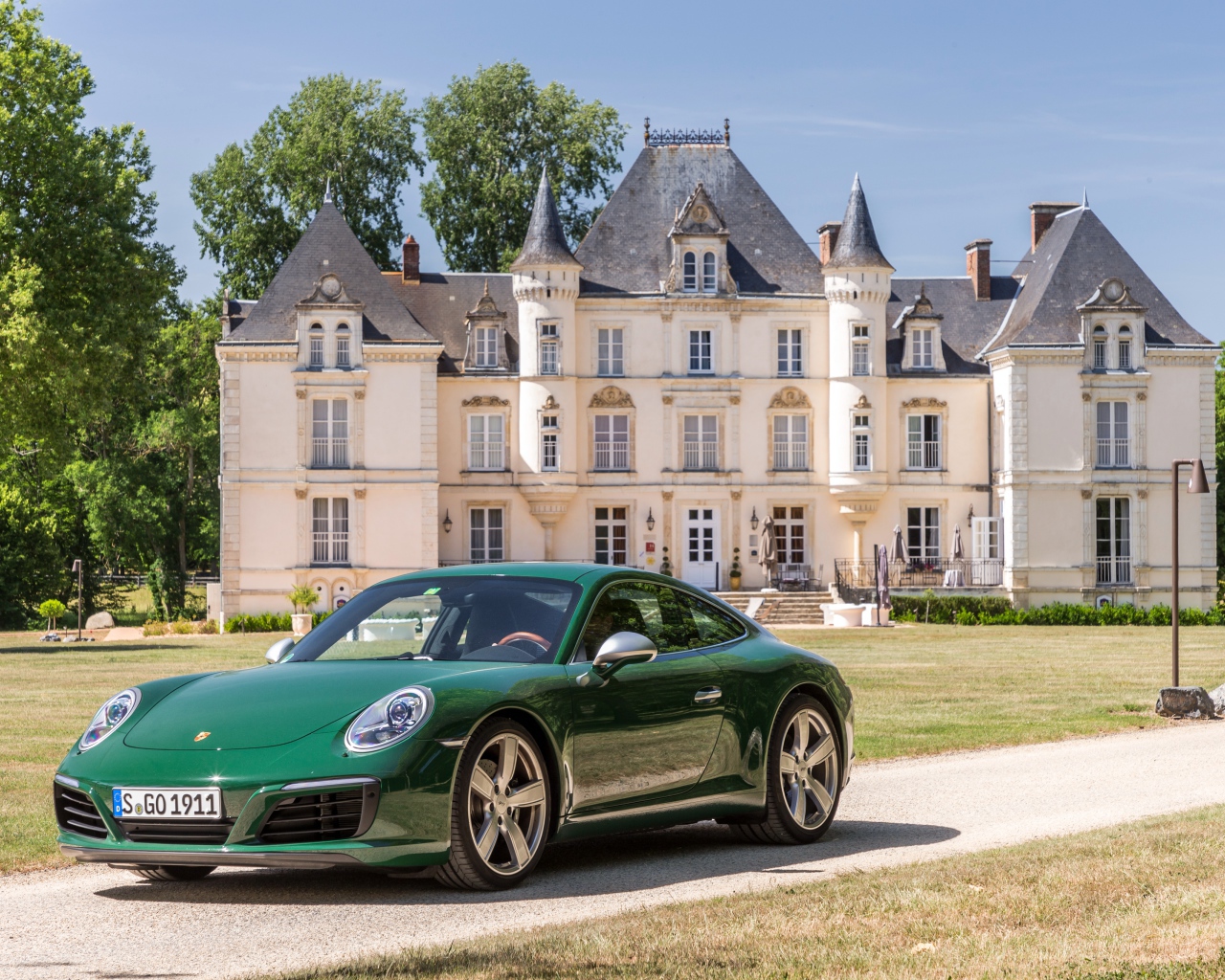 Зеленый спортивный автомобиль Porsche 911 Carrera на фоне дома