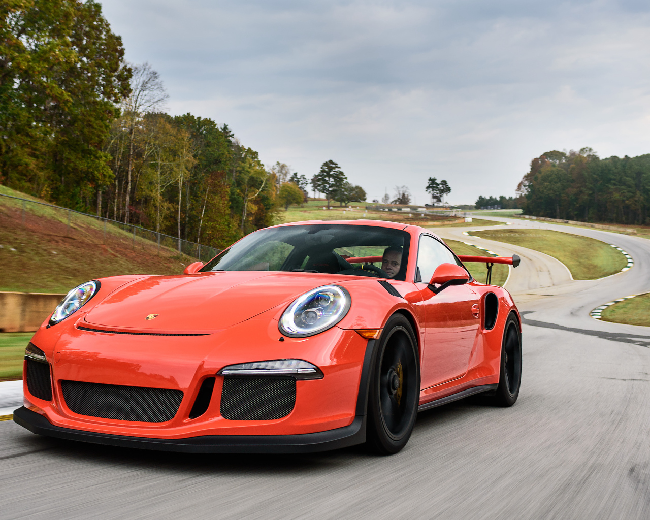 Оранжевый спортивный автомобиль Porsche 911 GT3 на трассе