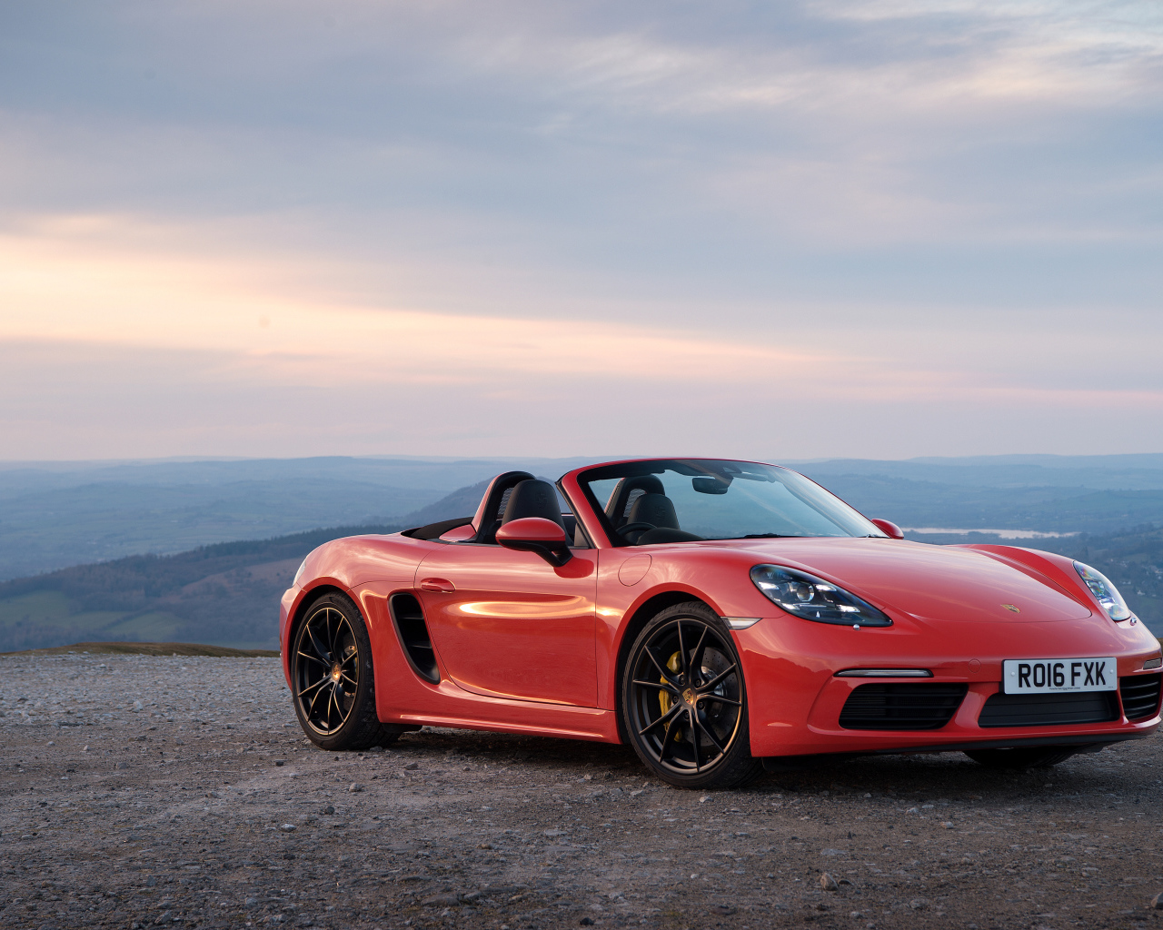 Красный автомобиль кабриолет Porsche 718 Boxster на фоне горизонта 