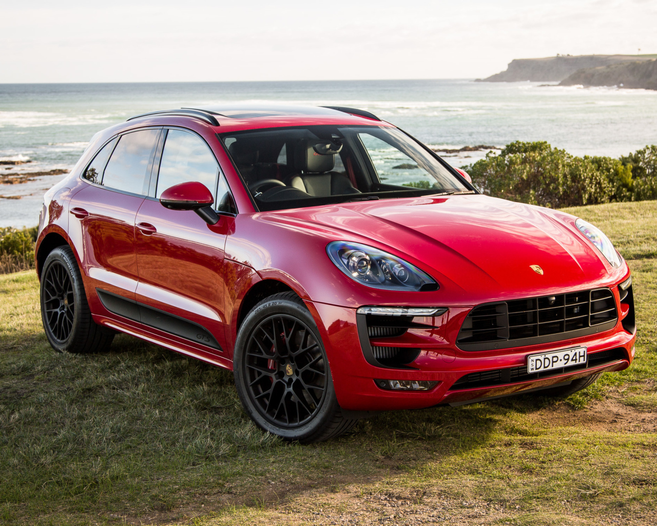 Красный автомобиль Porsche Macan,2017 на фоне океана 