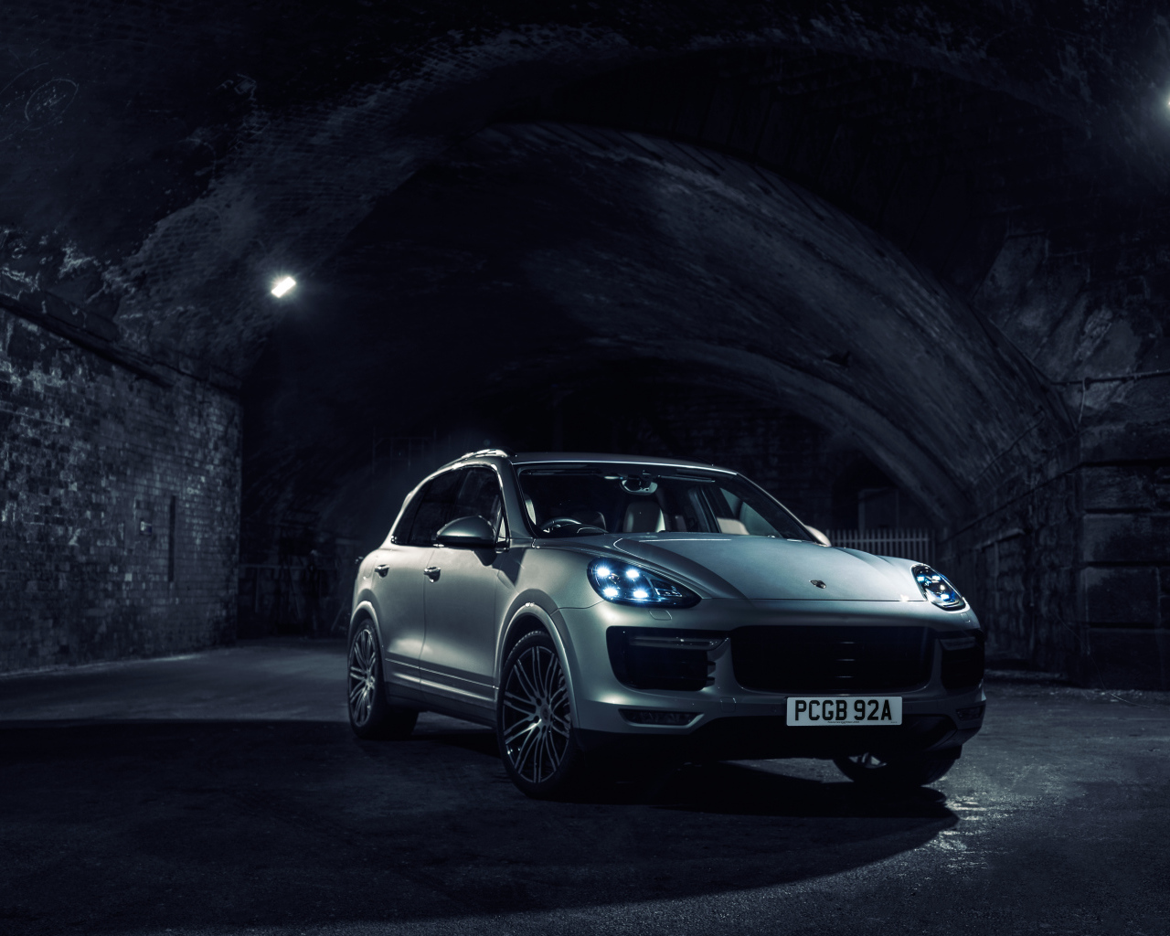 Silver Porsche Cayenne in a tunnel with lights on