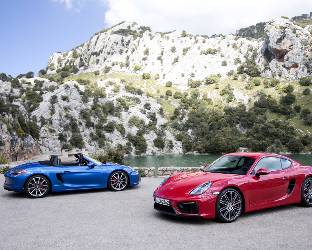 Два спортивных автомобиля Porsche Boxster и Porsche Cayman GTS  у воды 