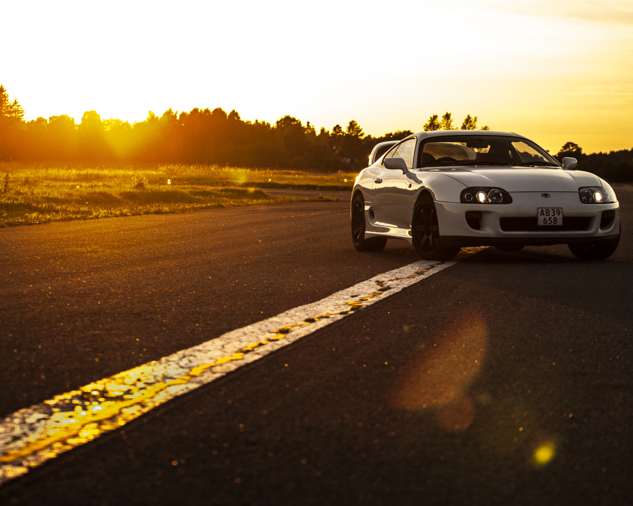 Белый автомобиль Toyota Supra стоит на трассе на рассвете