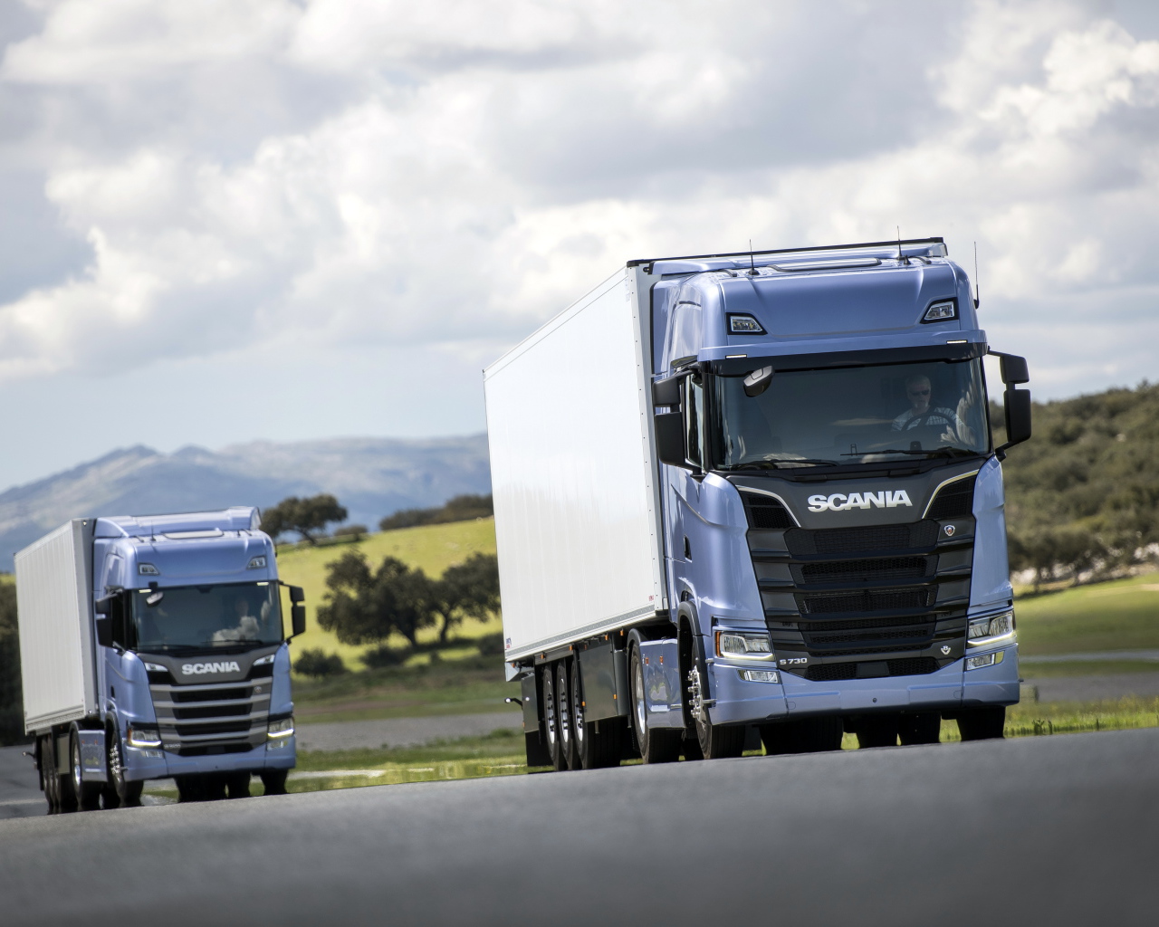 Два голубых грузовика Scania S 700 на трассе