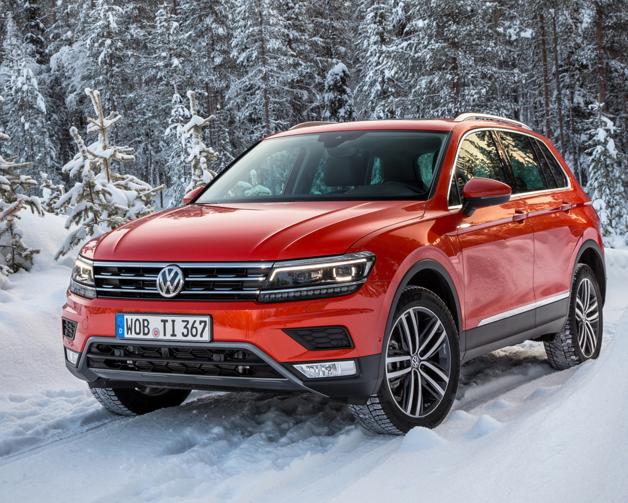 Красный Volkswagen Tiguan 2017 года в заснеженном лесу 