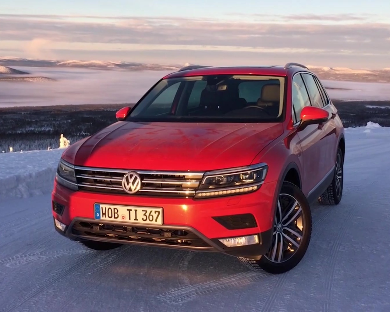 Красный Volkswagen Tiguan 2017 года на заснеженной трассе 