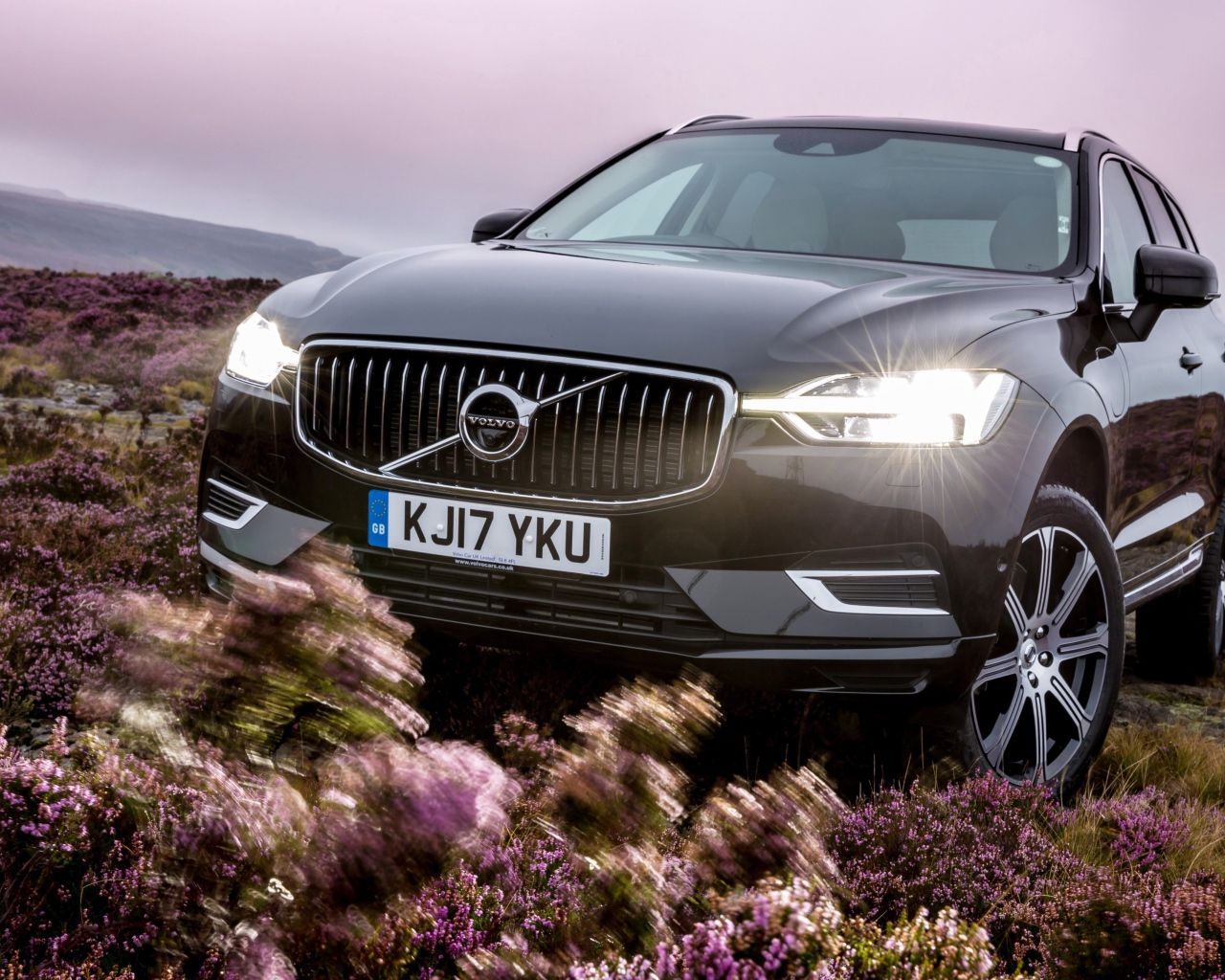 Черный автомобиль Volvo XC60 T8, 2018 с включенными фарами
