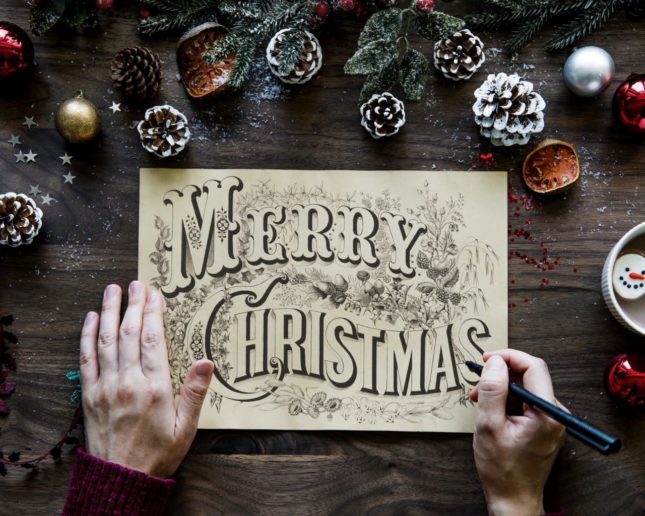 A drawing with the inscription Merry Christmas on the table with Christmas decorations