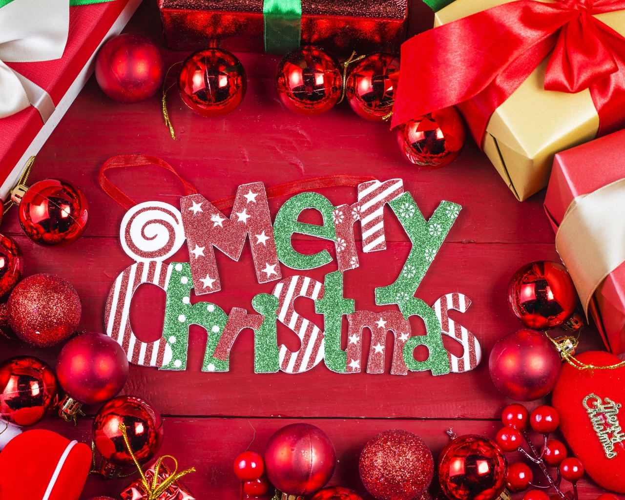 Праздничная надпись Merry Christmas на красном фоне с игрушками и подарками