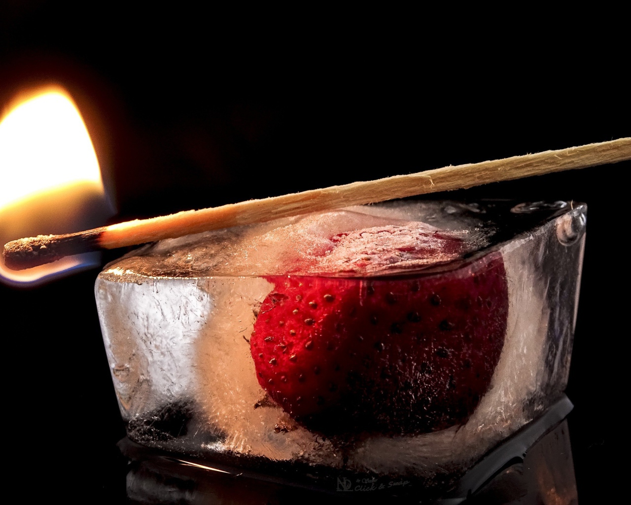 Зажженная спичка на кусочке льда с клубникой 