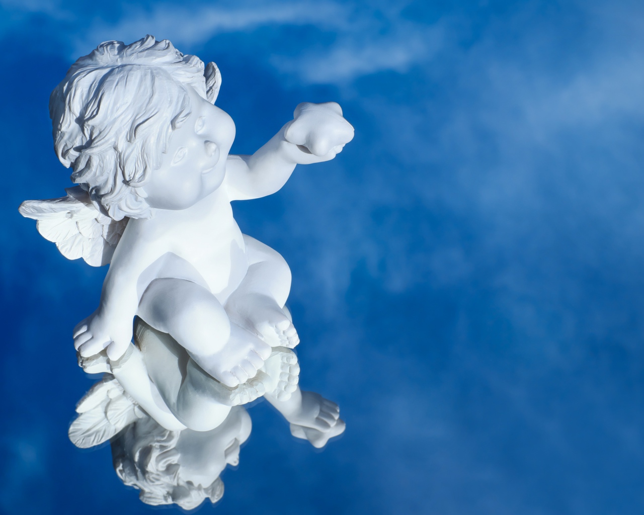 Маленькая статуя купидона отражается в голубой поверхности