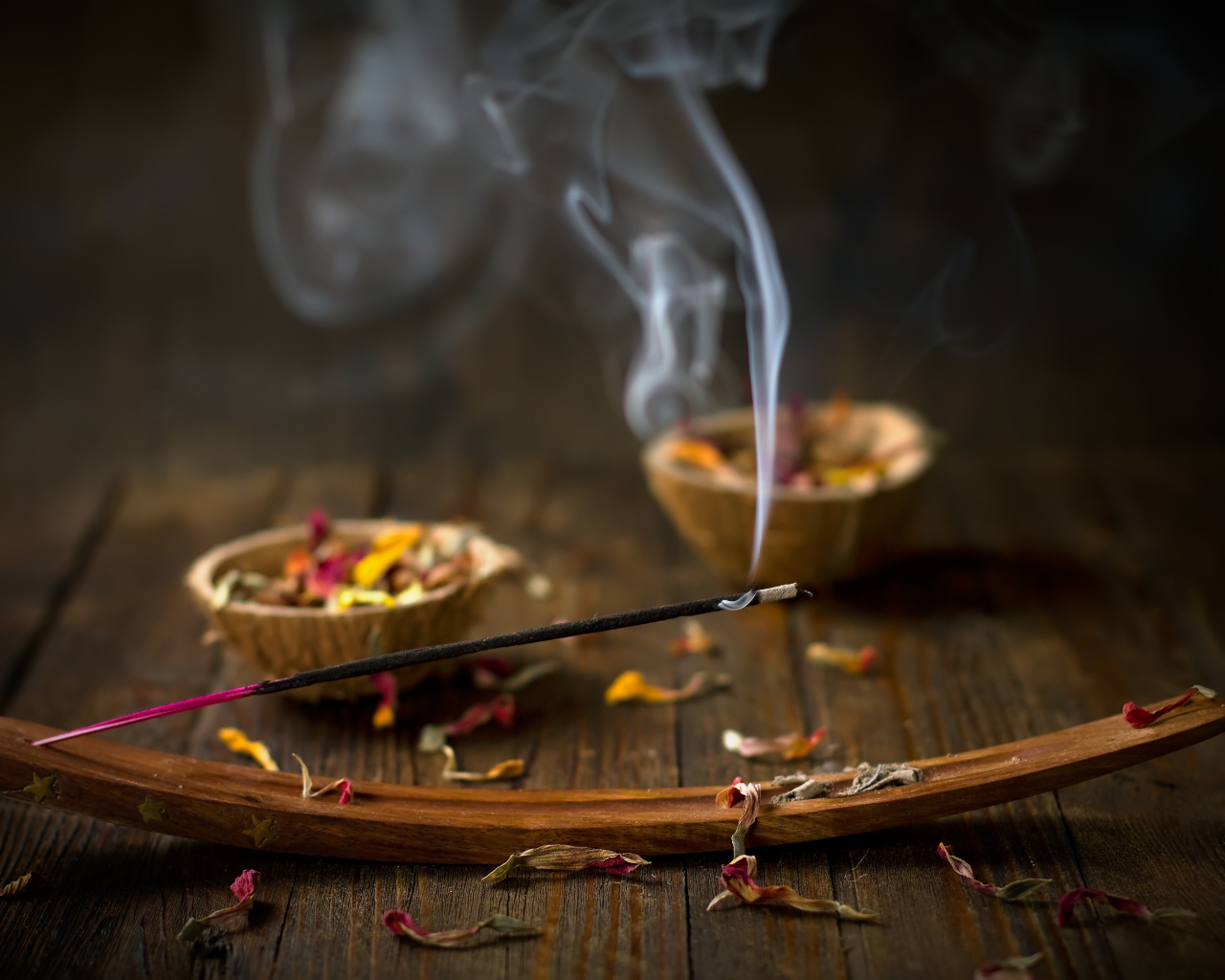 Ароматическая палочка на столе с сухими лепестками цветов