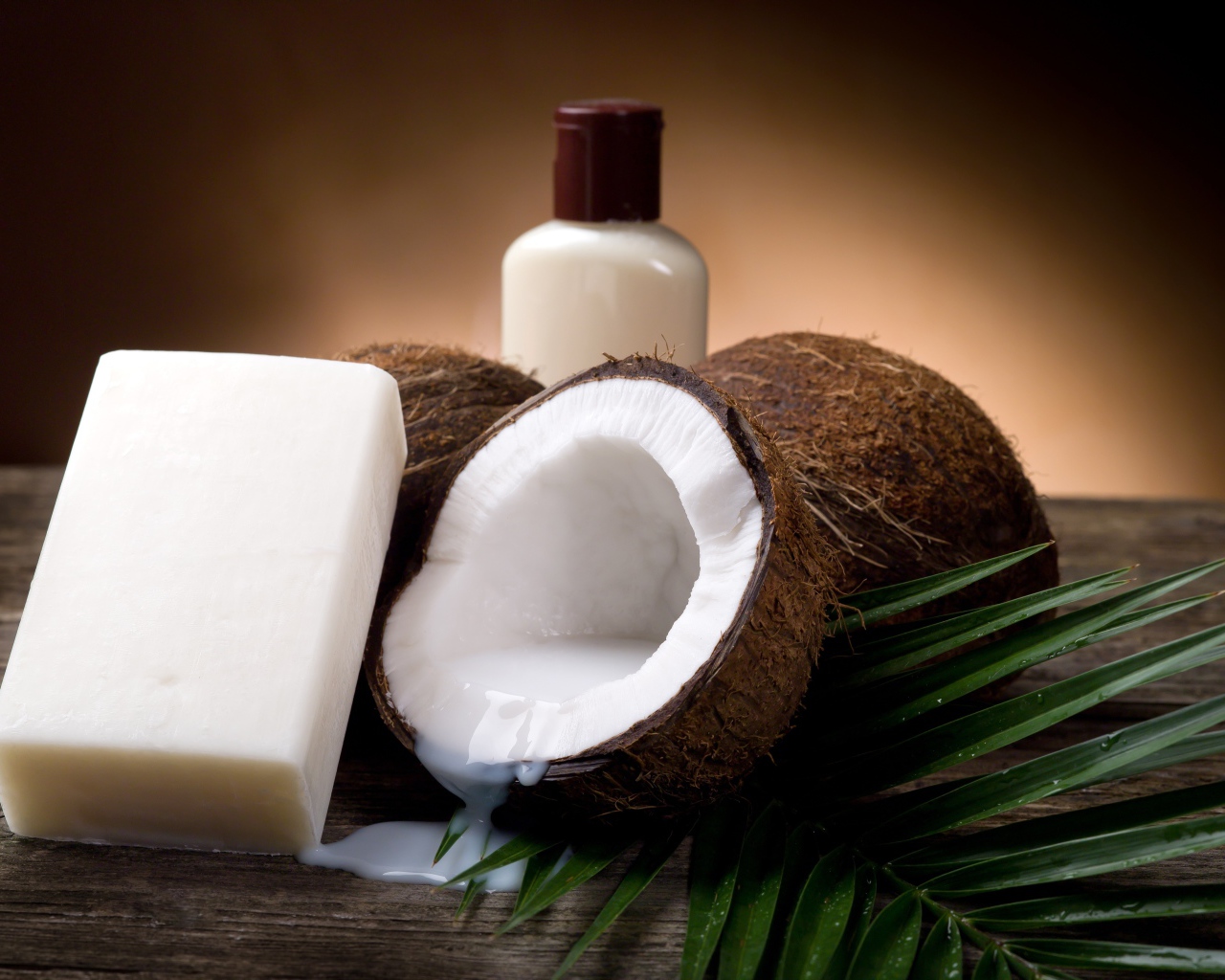 Кокосовое масло с кокосовым мылом и свежими кокосовыми орехами на зеленых листьях