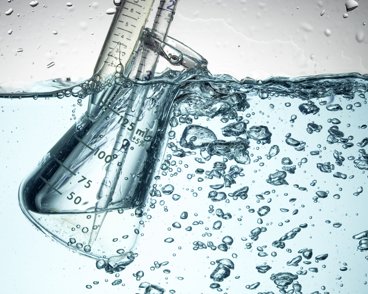 Измерительная чашка в воде с пузырями 