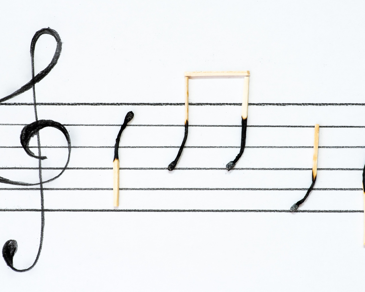 Ноты из сгоревших спичек на белом фоне