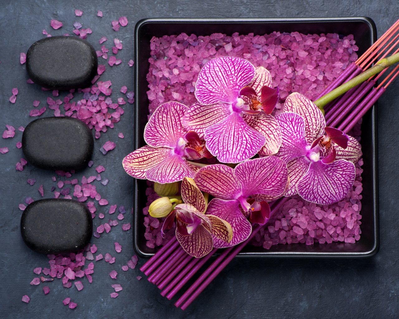 Цветы орхидеи с ароматическими палочками, камнями и солью