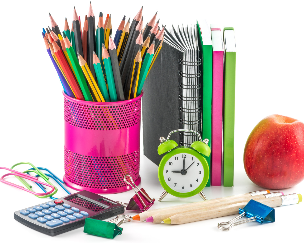 Канцелярские товары и красное яблоко на белом фоне