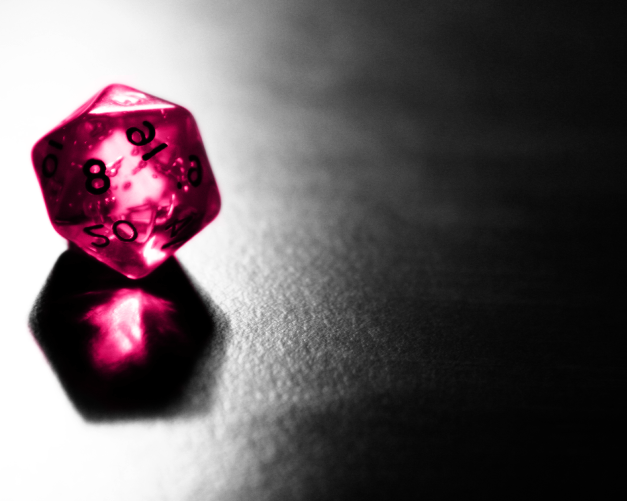 Розовый фигурный кубик отражается серой поверхности стола